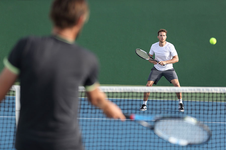 two tennis players hitting ball on outdoor court